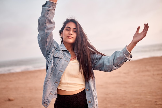 Young Latin woman smiles during a beautiful sunset Happy young woman with mask on the beach taking