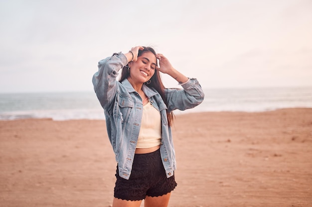 Young Latin woman smiles during a beautiful sunset Happy young woman with mask on the beach taking