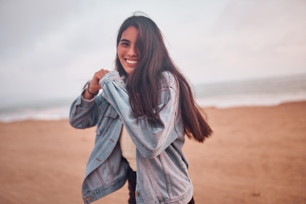 Young Latin woman smiles during a beautiful sunset Happy young woman with mask on the beach taking