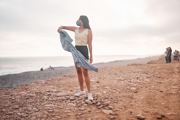 Young Latin woman smiles during a beautiful sunset Happy young woman with mask on the beach taking