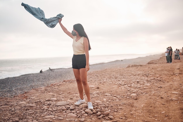 Young Latin woman smiles during a beautiful sunset Happy young woman with mask on the beach taking