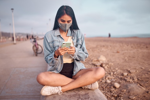 young Latin woman smiles during a beautiful sunset Happy young woman with mask