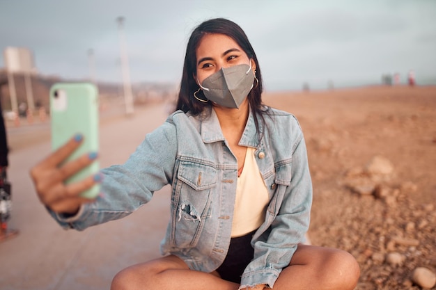 young Latin woman smiles during a beautiful sunset Happy young woman with mask