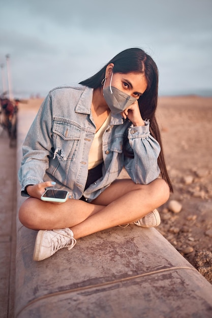 young Latin woman smiles during a beautiful sunset Happy young woman with mask