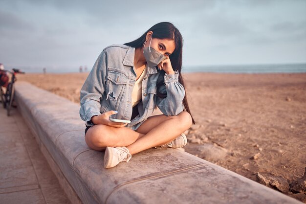 young Latin woman smiles during a beautiful sunset Happy young woman with mask