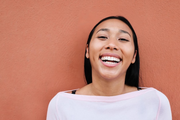 Young latin woman smiling on camera outdoors in the city - Focus on face