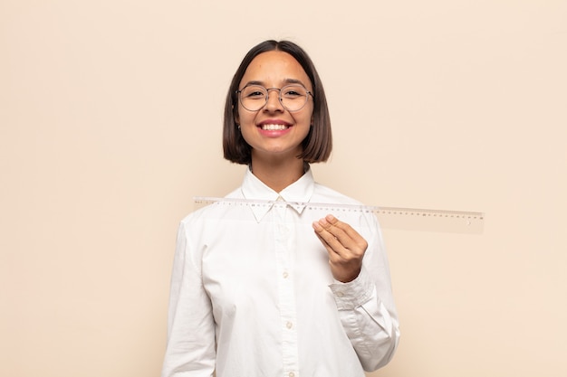 Young latin woman smiling happily with a hand on hip and confident, positive, proud and friendly attitude