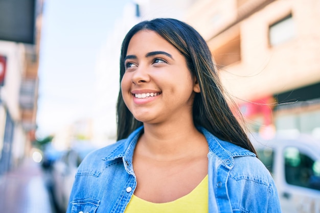 Young latin woman smiling happy walking at street of city.