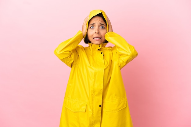 Young latin woman wearing a rainproof coat over isolated background doing nervous gesture