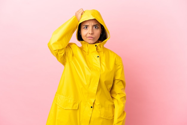 Young latin woman wearing a rainproof coat over isolated background with an expression of frustration and not understanding