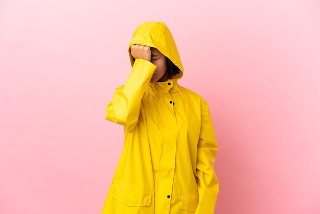 Young latin woman wearing a rainproof coat over isolated background with headache