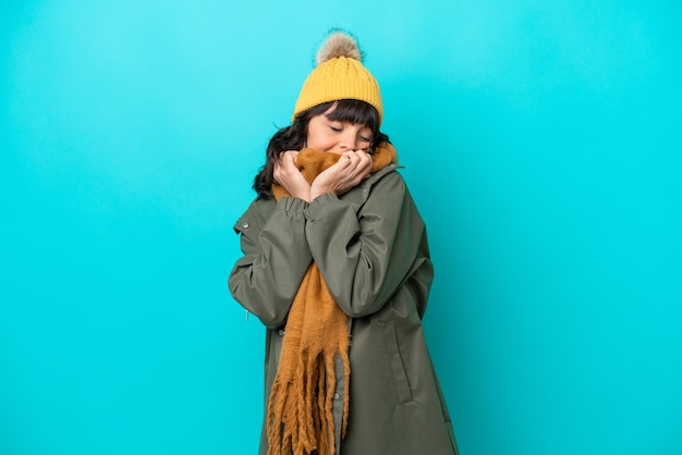 Young latin woman wearing winter jacket isolated on blue background