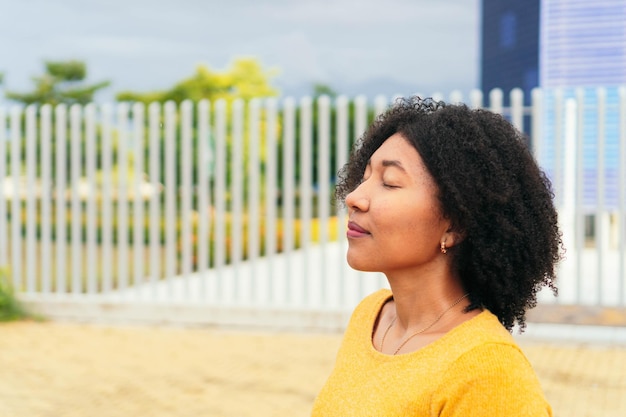 Young latina with her eyes closed while standing in the park