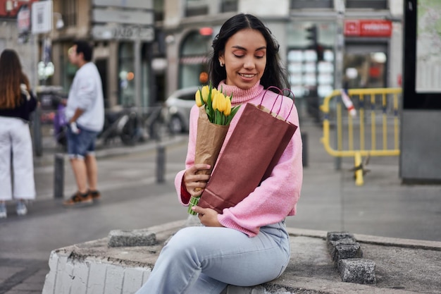 Young Latina woman with yellow tulips and wine spreading love and joy through a romantic surprise