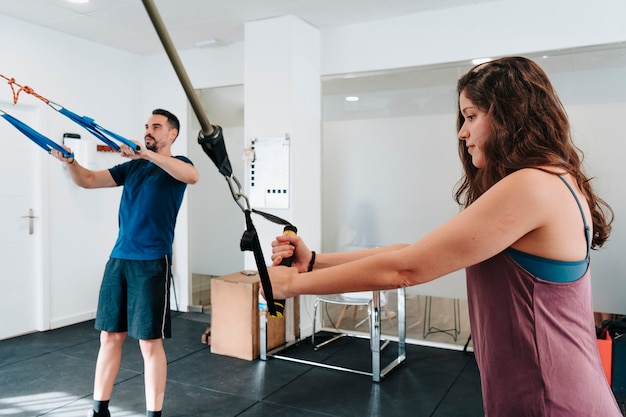 Young Latino boy and girl doing arm exercises with the help of a personal trainer