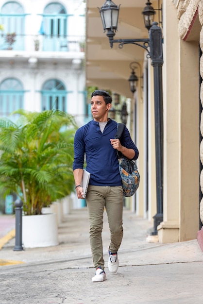 Young latino man walking down the street with his laptop Panama city Central America