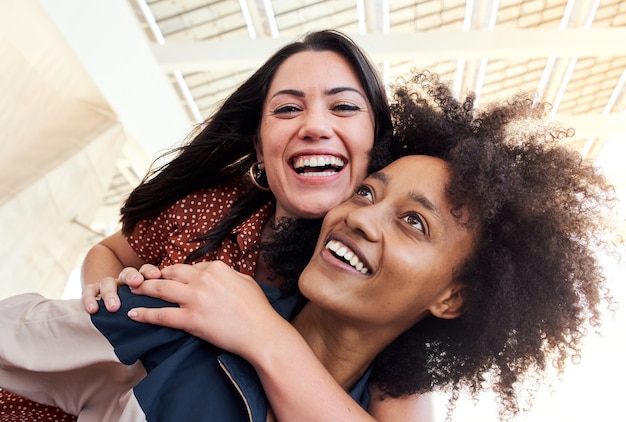 Young lesbian couple in love smiling looking at camera the girl is riding a piggyback to her friend