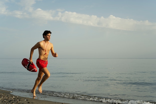 Young lifeguard running on beach full shot