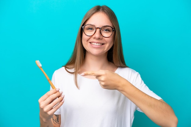 Young Lithuanian woman brushing teeth over isolated background and pointing it