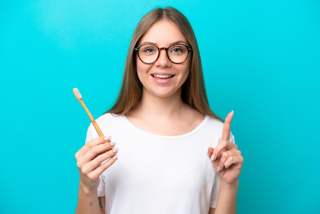 Young Lithuanian woman brushing teeth over isolated background pointing up a great idea