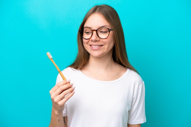 Young Lithuanian woman brushing teeth over isolated background with happy expression