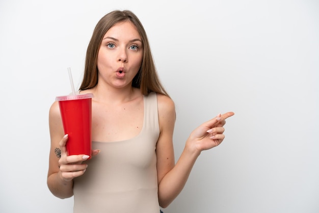 Young Lithuanian woman holding refreshment isolated on white background surprised and pointing side