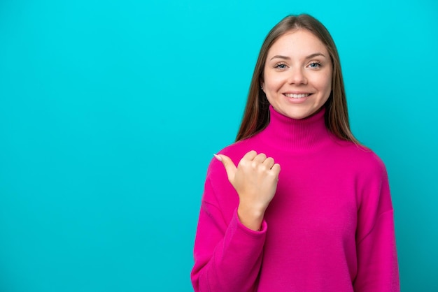 Young Lithuanian woman isolated on blue background pointing to the side to present a product