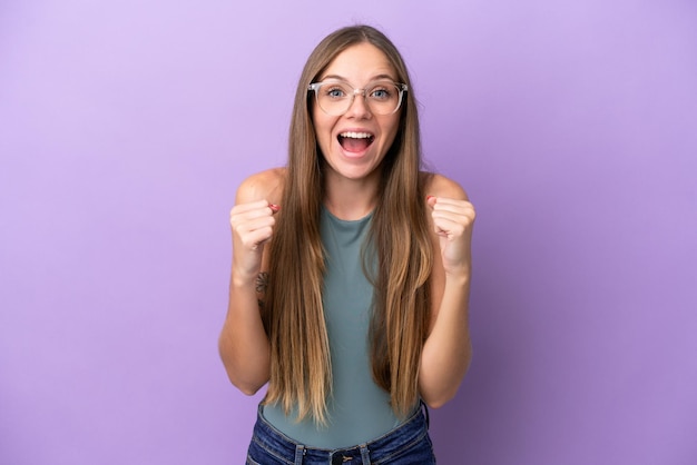 Young Lithuanian woman isolated on purple background celebrating a victory in winner position