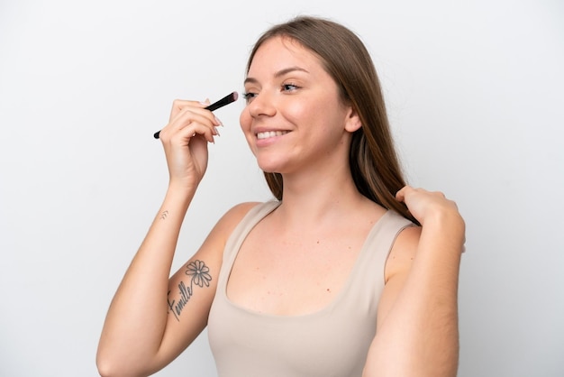 Young Lithuanian woman isolated on white background holding makeup brush