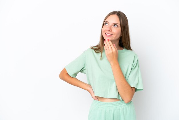 Young Lithuanian woman isolated on white background looking up while smiling