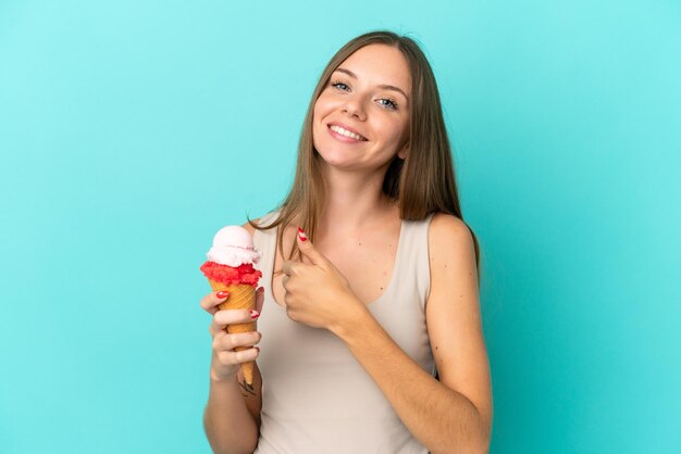 Young Lithuanian woman with cornet ice cream isolated on blue background giving a thumbs up gesture