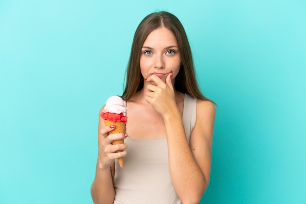 Young Lithuanian woman with cornet ice cream isolated on blue background thinking