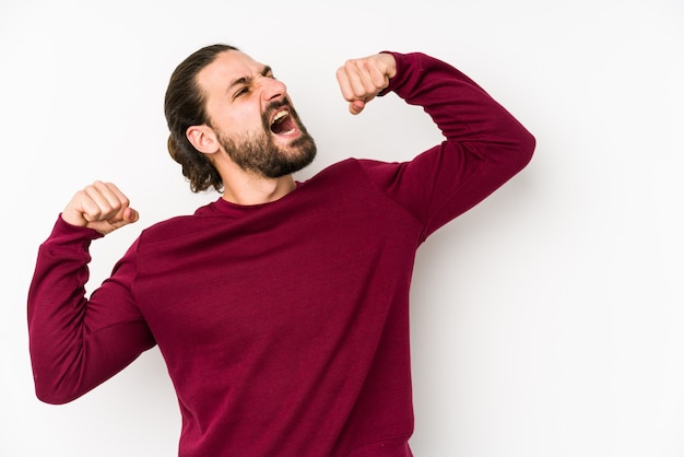 Young long hair man isolated on a white wall raising fist after a victory