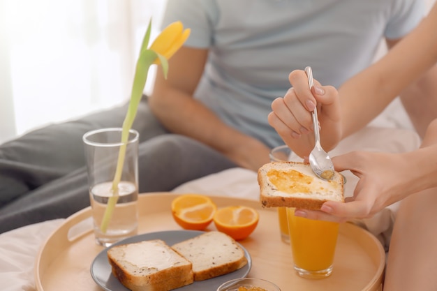 Young lovely couple having breakfast on bed