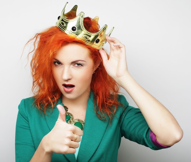 Young lovely redhair woman in crown, studio