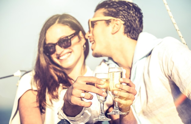 Young lovers couple on sailboat with focus on champagne flute glass cheer