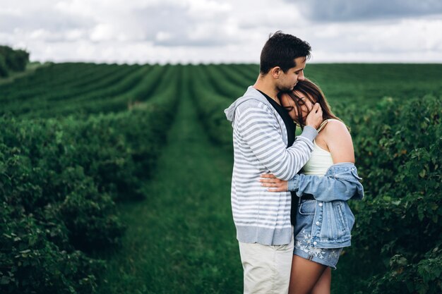 Young loving couple gently hugging on the green currant plantations. Love Story