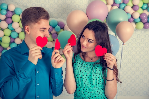 Young, loving couple, kiss each other, cover their lips with a candy in the form of a heart