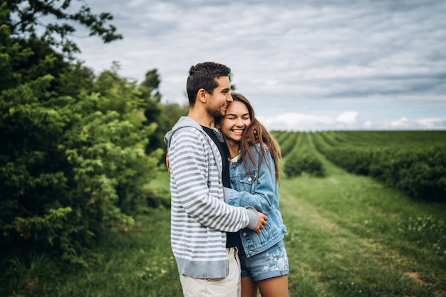 Young loving couple, woman and man, gently hugging with eyes closed on green field. Love Story