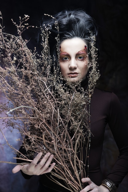 Young luxury woman with bright makeup holding a bunch of dry twi