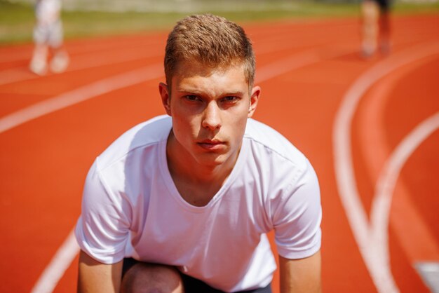 Photo young male athlete preparing for a race on a running track