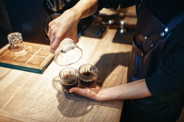 Young male barista makes fresh black coffee