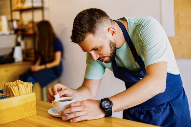 Young male barista prepares coffee