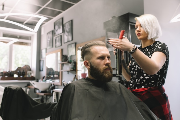 Young male client of a barber shop with water from a bulb. Haircut, styling beard.