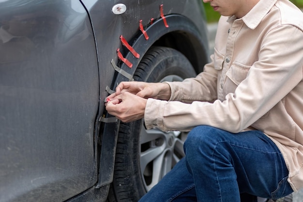 A young male driver repairs a car wing after an accident on the road