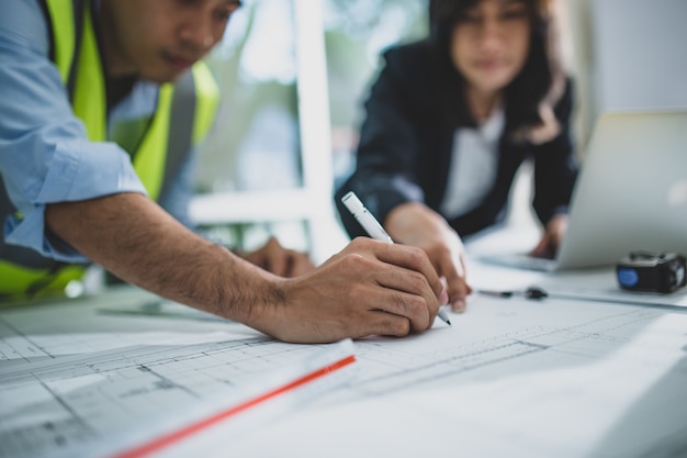 Young male and female architect colleagues drawing graphic planning of interior creation project cooperating with talented teacher giving advice and correcting mistakes during training lesson