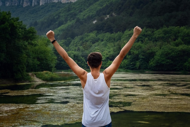 The young male hipster looking at the beautiful view at the lake