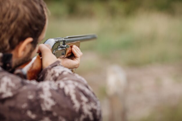 Young male hunter in camouflage clothes ready to hunt with hunting rifle