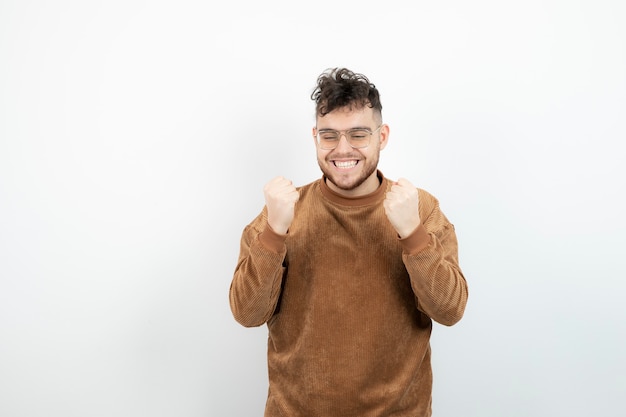 young male model standing and looking over white wall. 