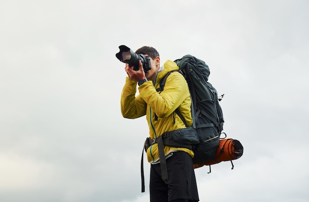 Young male photographer with his professional camera taking pictures of beautiful nature